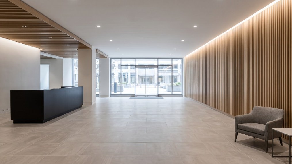 Renovated Class-A building lobby with reception desk and architectural wood accents.
