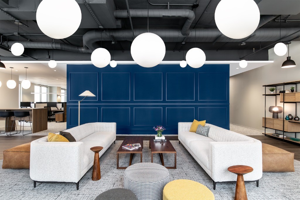 High-end tenant collaboration area with custom blue wainscoting and modern pendant lighting.
